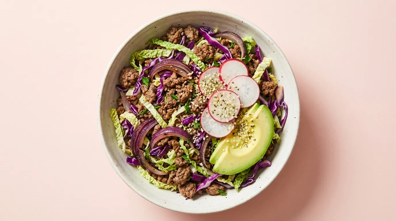 High-protein ground beef and cabbage bowl with seared lean meat and bright green shredded vegetables in a ceramic bowl.